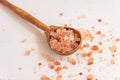 Fine himalayan salt in a wooden scoop on a white background