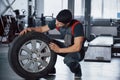 Fine material. Mechanic holding a tire at the repair garage. Replacement of winter and summer tires Royalty Free Stock Photo