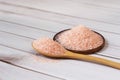 Fine pink Himalayan salt in wooden spoon on a white wooden background