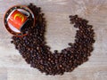 A fine porcelain ware tea coffee cup and a saucer in red, black and yellow, spilled coffee beans on oak wood rustic background. Royalty Free Stock Photo