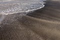 Fine white sand beach, brindle with black volcanic sand on Bali island. An interesting effect created by sea waves. Royalty Free Stock Photo