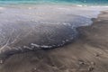 Fine white sand beach, brindle with black volcanic sand on Bali island. An interesting effect created by sea waves. Royalty Free Stock Photo