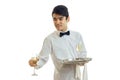 Fine young waiter looks sideways smiles and takes a glass of wine with a tray Royalty Free Stock Photo