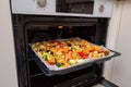 Finely chopped and seasoned vegetables on a baking sheet lined with baking paper in the oven. Potatoes, bell peppers, squash, Royalty Free Stock Photo