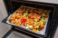 Finely chopped and seasoned vegetables on a baking sheet lined with baking paper in the oven. Potatoes, bell peppers, squash, Royalty Free Stock Photo