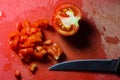 Finely chopped tomato with knife on a red rough chopping board Royalty Free Stock Photo