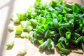 Finely chopped young green onions, on a wooden Board, the morning bright sun. Royalty Free Stock Photo