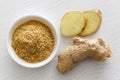 Finely ground dry ginger in white ceramic bowl on white