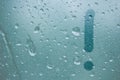 A finger drawing of the shape of an exclamation mark stripe on a semitransparent foggy glass. raindrops of spring rain on the