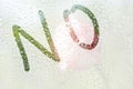 A finger drawing of the shape of the strips of the word no on a semitransparent misted glass. raindrops of spring rain on the