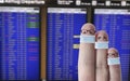 Finger face family with masks in front of flight timetable on airport
