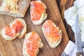 Finger food. Appetizer canapes sandwiches with baguette, salmon and butter on rustic wooden board over wood background. Top view,