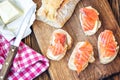 Finger food. Appetizer canapes sandwiches with baguette, salmon and butter on rustic wooden board over wood background. Top view,