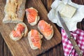 Finger food. Appetizer canapes sandwiches with baguette, salmon and butter on rustic wooden board over wood background. Top view,