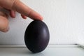 FInger holding a Painted Easter Boiled Egg isolated on a White Wall