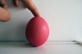 FInger holding a Painted Easter Boiled Egg isolated on a White Wall