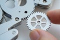 Human Finger Inserting Small Gear into Larger Metallic Gear System Displaying Interconnection in Macro Studio Shot and Isolated Royalty Free Stock Photo