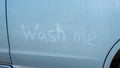 Finger lettering wash me in a dirty blue car. Royalty Free Stock Photo