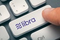 Finger pressing computer key with libra coin logo. crypto mining concept