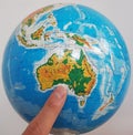 A finger pointing at Australia on a globe