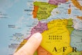 Finger pointing to a colorful country map in English and French of Morocco in North Africa