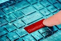 A finger press red download button on blue laptop keyboard Royalty Free Stock Photo