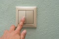 Finger presses an electronic light switch on a blue wall background Royalty Free Stock Photo
