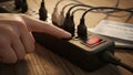 Finger pressing power switch on overloaded power strip Royalty Free Stock Photo