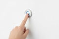 A finger presses a round glowing button on the wall. Space for text. Royalty Free Stock Photo