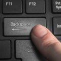A finger pressing the `Backspace` key on the black keyboard Royalty Free Stock Photo
