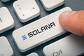 Finger pressing computer key with solana token logo