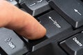 Finger pressing the enter key on a simple black computer keyboard, object macro, extreme closeup, side view. Confirmation, sending Royalty Free Stock Photo