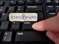 Finger pressing Enter key with sticky note with word RANSOMWARE placed on keyboard Royalty Free Stock Photo