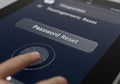 Finger pressing fingerprint scanner on digital screen for password reset authentication