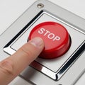 A finger pressing a large red stop button on a control panel Royalty Free Stock Photo