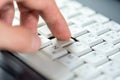 Finger pressing one single key on a white laptop keyboard, shallow dof, object macro, detail, extreme closeup. Using a computer Royalty Free Stock Photo