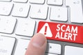 Finger pressing red key labeled SCAM ALERT on computer keyboard Royalty Free Stock Photo