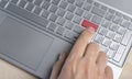 Finger pressing red warning button on laptop computer Royalty Free Stock Photo