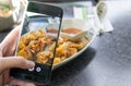 Finger pressing on smartphone for photograph chinese food in res Royalty Free Stock Photo