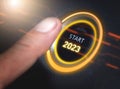 Finger pressing a 2023 start button. Concept of new year, two thousand twenty three. Composite between a photography and a 3D Royalty Free Stock Photo