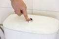 Finger pushing button and flushing toilet. Royalty Free Stock Photo