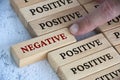 Finger pushing negative text on wooden block from the rest of the wooden blocks with positive text. Positive mindset