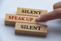 Finger pushing wooden block with red written text speak up. Courage and speak up concept