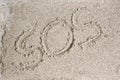 Finger on the sand of the word SOS. Royalty Free Stock Photo