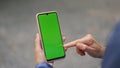 Finger tapping green smartphone closeup. Woman hand scrolling chroma key device