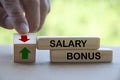 Finger turning wooden block changing the arrow direction up and down for salary and bonus. Salary and bonus increment