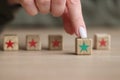 Finger of woman touches kids wooden cube with green star