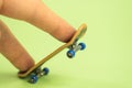 Fingerboard. Man playing by two fingers with small skateboard on green background