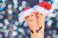 Fingers art of couple celebrates Christmas. Concept of man and woman hug in new year hats.