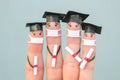 Fingers art of students in medical mask from COVID-2019. Graduates holding their diploma after graduation